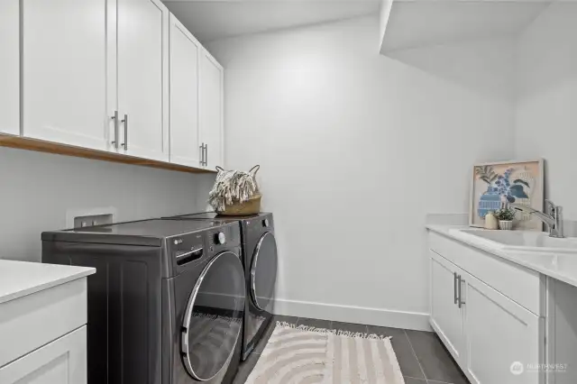 Spacious laundry room with sink, cabinets and counterspace.