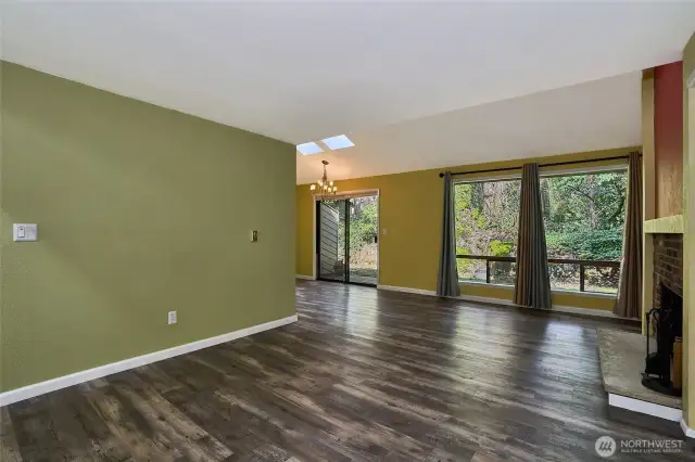 Bright living room with large windows and updated vinyl plank flooring.