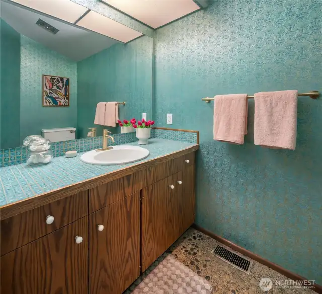 Upper level powder room with aggregate flooring that matches the entryway and a sweet tile countertop.
