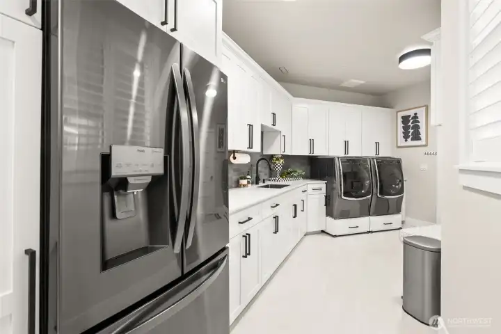 A large mud room with numerous cabinets and extra refridgerator space.