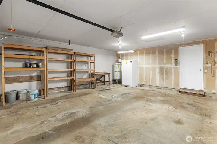 Large two car garage with shelves and a standing freezer