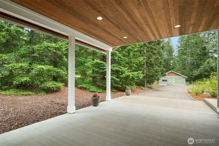Tongue & groove wood-panel ceiling makes the rear drive-through carport an excellent covered patio for outdoor entertaining in any weather.