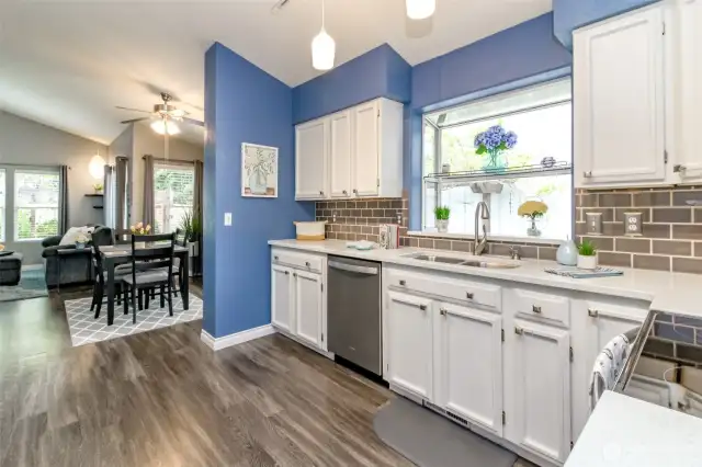 This kitchen is not only functional but beautiful! With its white cabinets, quartz counters, plant window and vinyl floors, who wouldn't want to cook in here?