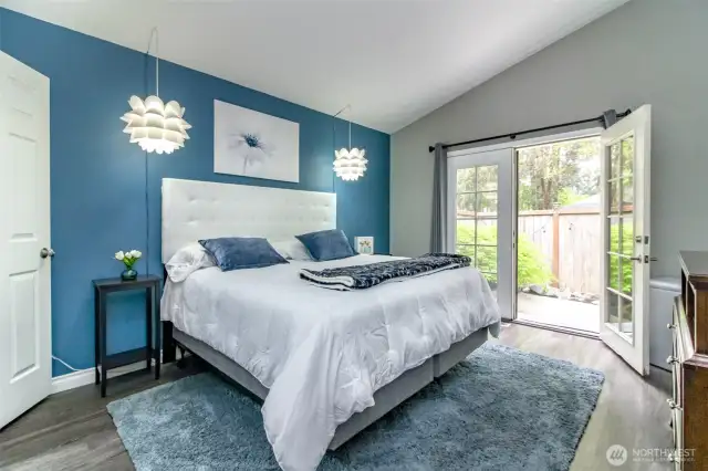 Beautifully appointed main bedroom with custom paint, vaulting ceiling and light fixtures. French doors leading out to the outside gardens.