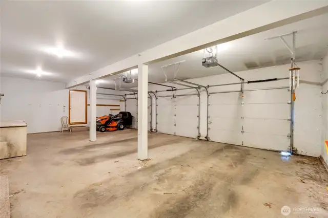 Spacious three-car garage with a working sit-on tractor and large functional freezer included.