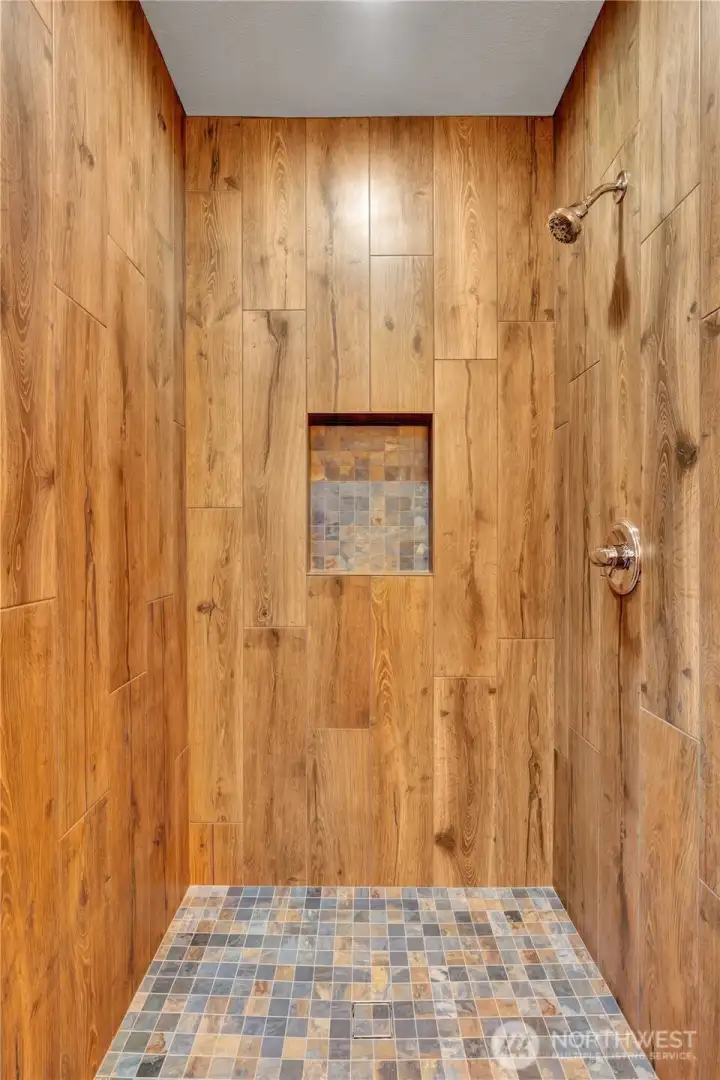 Walk in shower with stone tile.