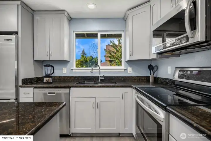 Beautifully remodeled kitchen featuring sleek gray shaker cabinets, rich granite countertops, and stainless-steel appliances.