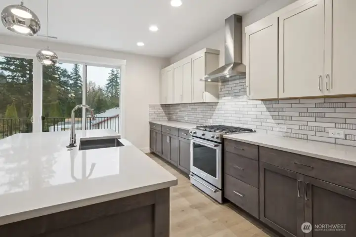 Gorgeous kitchen with quartz counters, gas range/oven, full height backsplash, and huge island.