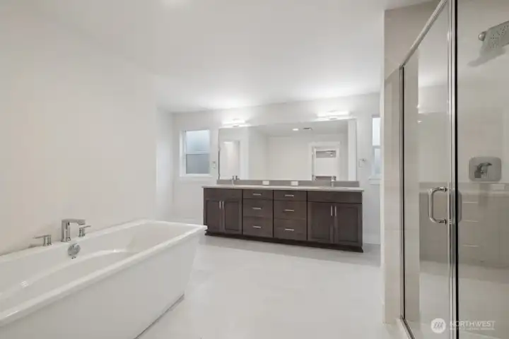 spa-like primary bathroom with soaking tub, walk in shower, and double vanity.