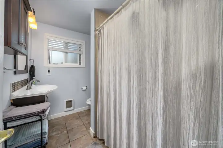 Unit 2 - Spacious full bathroom featuring a wide vanity with updated fixtures, overhead lighting, and extra storage. Neutral tile floors and a large shower/tub combo provide everyday comfort and functionality.