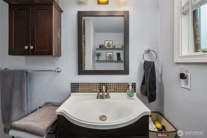 Unit 2 - More views of the clean and practical bath layout, including built-in cabinetry, modern finishes, and a frosted window that brings in natural light while maintaining privacy.