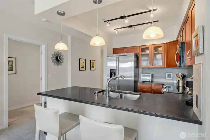 The timeless kitchen features shaker-style cabinetry, honed granite counters with bar-top seating, and stainless steel GE appliances.