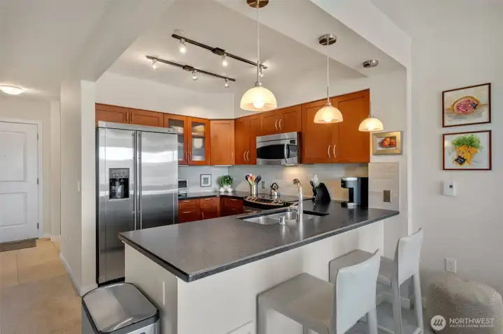 The timeless kitchen features shaker-style cabinetry, honed granite counters with bar-top seating, and stainless steel GE appliances.