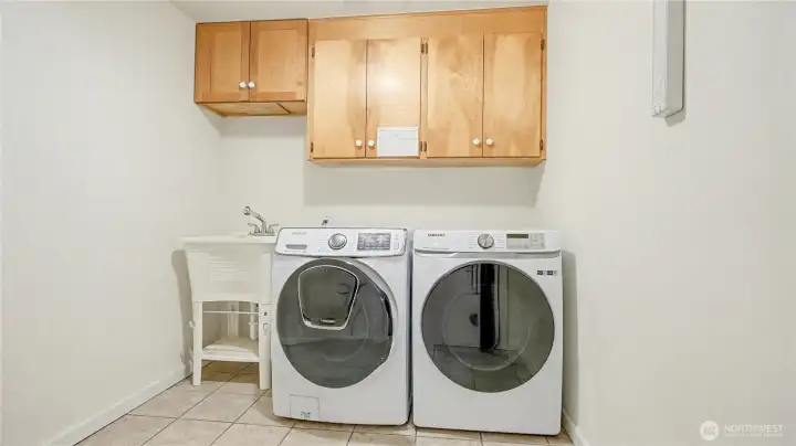 Spacious laundry room with matching white washer & dryer, utility sink and convenient storage.