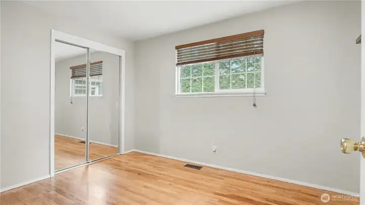 First guest bedroom offering neutral paint color and mirror closet doors.