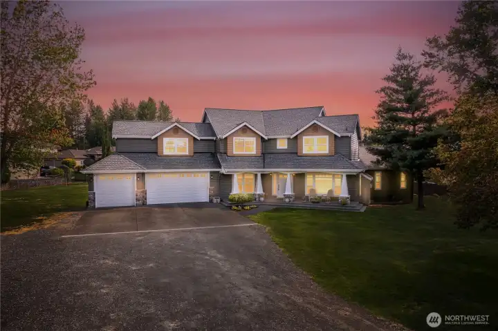Stunning twilight exterior showcasing the timeless Craftsman architecture, welcoming covered front porch, and beautifully manicured grounds set on 1.21 private acres in one of Snohomish’s most desirable locations.