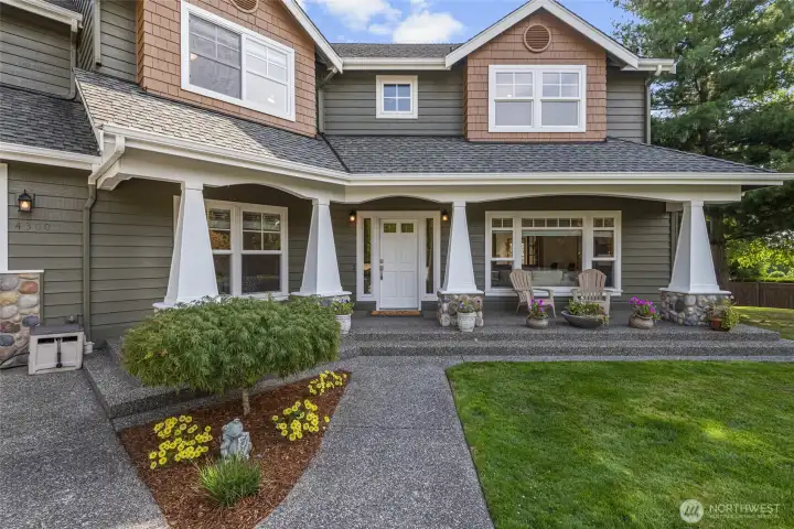 Inviting covered front porch with timeless Craftsman details, stone accents, and beautifully landscaped grounds.
