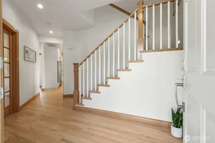 Bright and welcoming entry with soaring ceilings, hardwood floors, and an elegant staircase creating a warm first impression.