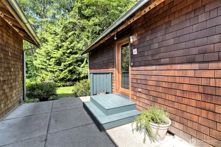Concrete patio located between the entrance door and the detached garage.