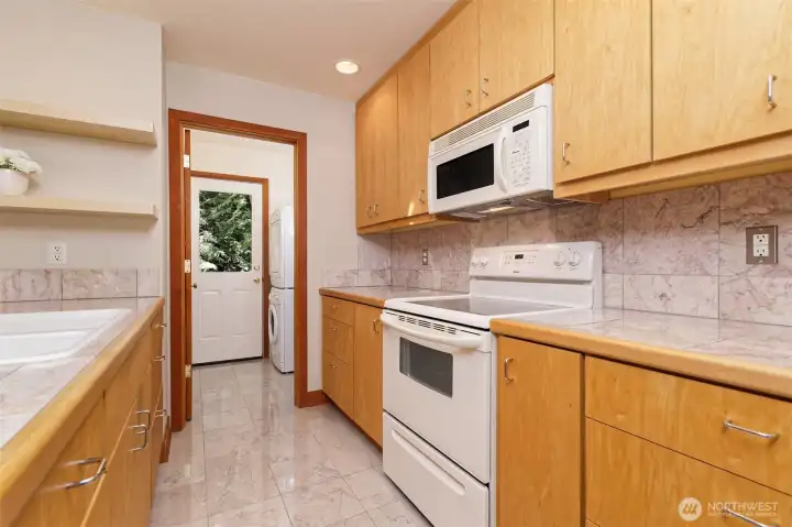 Spotless kitchen with tile counter tops and backsplash.
