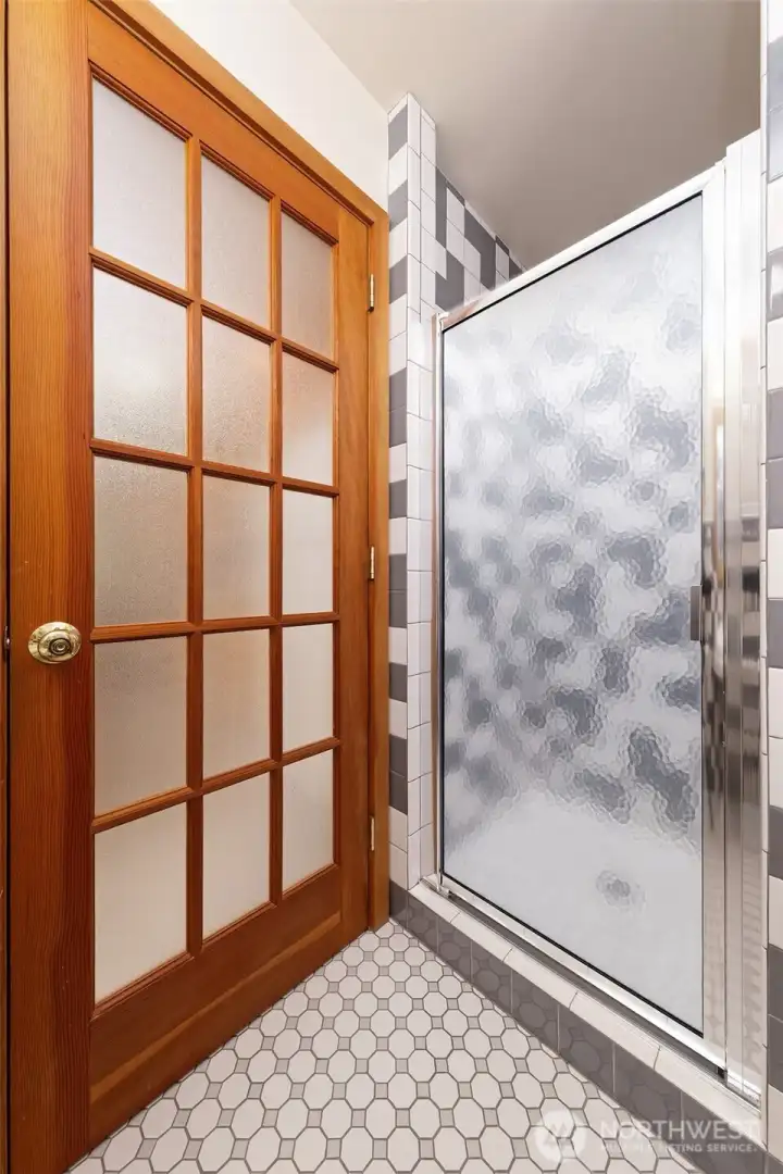 Frosted class panel entry door to the main bath and tiled shower looks like new.