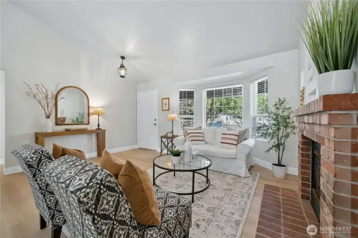 The living room is anchored by a cozy gas fireplace and a large bay window overlooking the beautiful front yard.