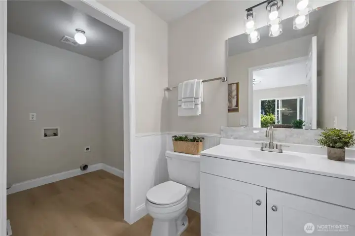 The updated half bath features a new vanity, backsplash, lighting and fixtures and is conveniently located next to the laundry room.