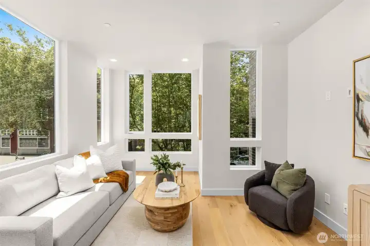 This window-lined living space is bathed in calming natural light, pulling the vibrant summer greenery indoors and giving you the serene sense of floating amongst the trees.(photos are of model home, similar finishes and floorplan)
