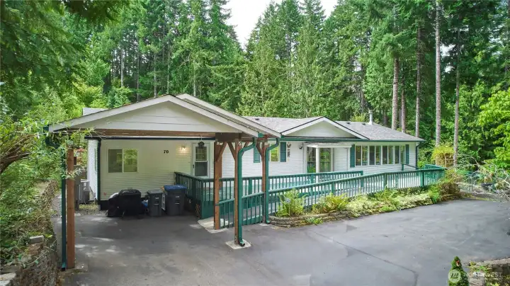 This charming manufactured home features low-maintenance vinyl siding, a large covered carport, and an expansive wrap-around deck perfect for outdoor relaxation and entertaining.