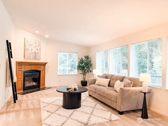 A second inviting living space features a handsome wood-mantel fireplace, comfortable plush carpeting, and large picture windows looking out into the peaceful backyard.