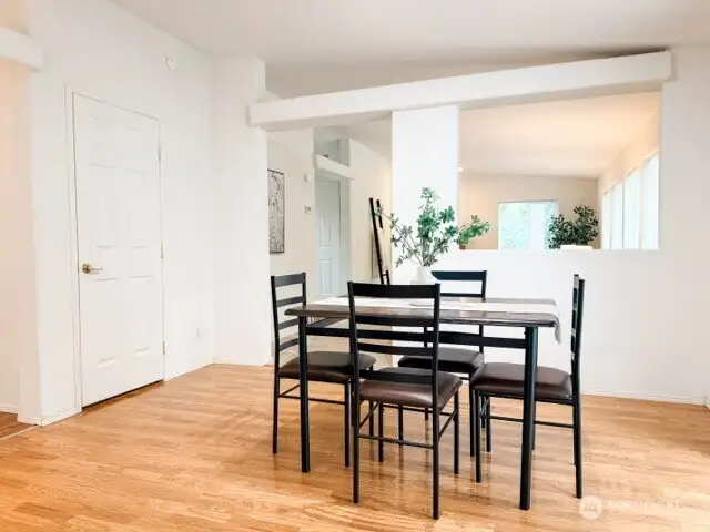 The dedicated dining space boasts warm wood floors and an architectural pass-through window, keeping the home feeling connected, airy, and full of natural light.