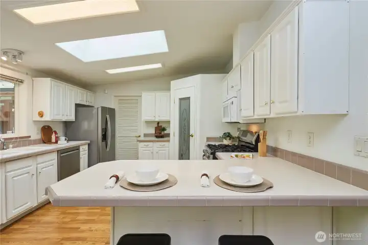The generous breakfast bar provides the perfect spot for casual morning coffee, quick meals, or entertaining guests while cooking under the bright, natural light of the skylights.