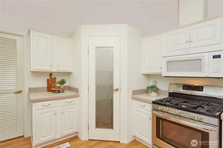 The kitchen offers exceptional storage and cooking space, highlighted by a dedicated walk-in pantry with a decorative frosted glass door, a modern gas range, and ample cabinet space.