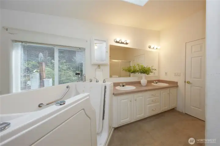 Designed for ease and comfort, the primary bathroom offers a long, double-sink vanity with excellent storage, bright vanity lighting, and a safe, accessible step-in jetted tub.