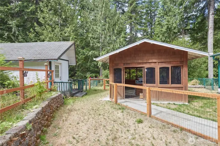 The fully fenced backyard area features a paved pathway connecting the cozy detached studio and the enclosed hot tub house, creating a private outdoor sanctuary.