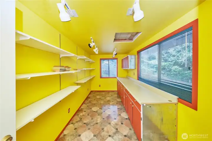 Step inside the vibrant, light-filled detached outbuilding—an ideal setup for a creative art studio, craft room, or home office with built-in countertops and shelving.