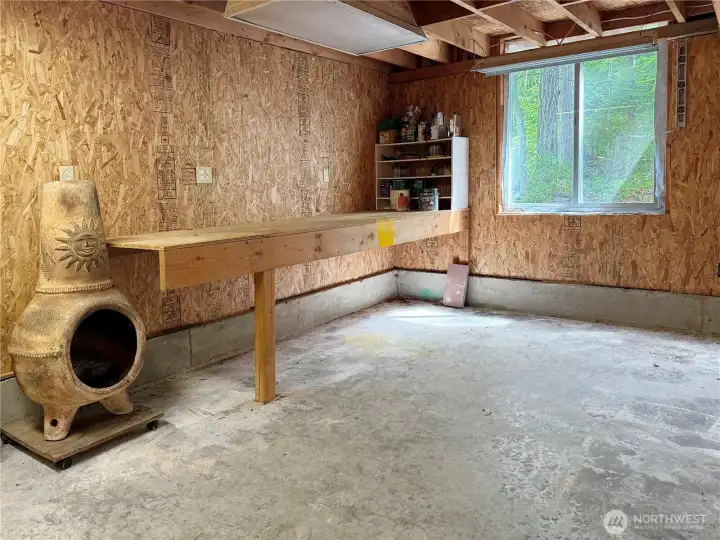 A handy workshop area within the garage, complete with a heavy-duty wooden workbench, dedicated storage shelves, and a window offering natural light.