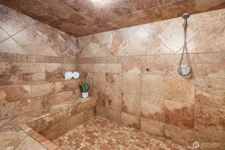 Massive steam shower with multiple seating areas.