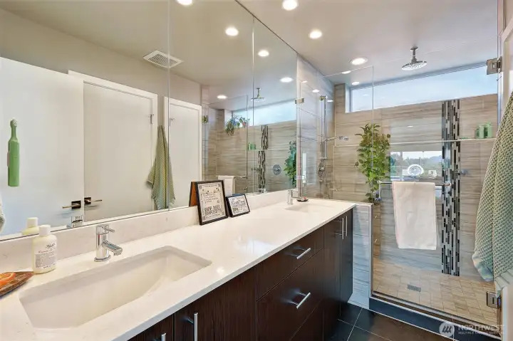 Primary bath includes a large tiled shower with rain shower head and dual sink vanity.