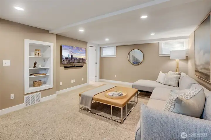 Lower-level media/family room with built-in bookshelves. The TV stays with the home.