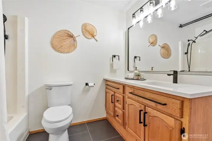 Full bath in upstairs hallway with new tile, new quartz counters and new fixtures.