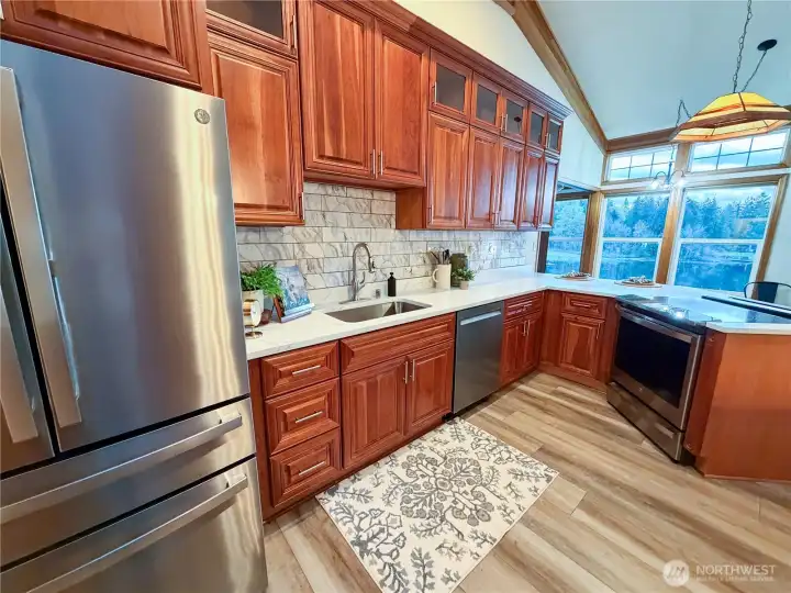 Gourmet kitchen featuring American cherry cabinetry, quartz countertops, & newer stainless appliances, including a French door refrigerator & induction cooktop