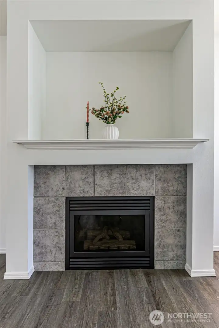 Gas fireplace with tile surround and wood mantle.