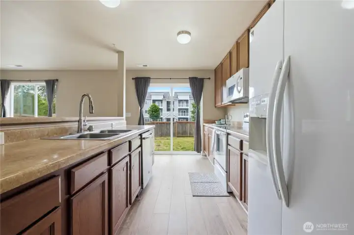 Kitchen with island that looks out to living room and sliding doors to the fully fenced yard Kitchen with island that looks out to living room and sliding doors to the fully fenced yard