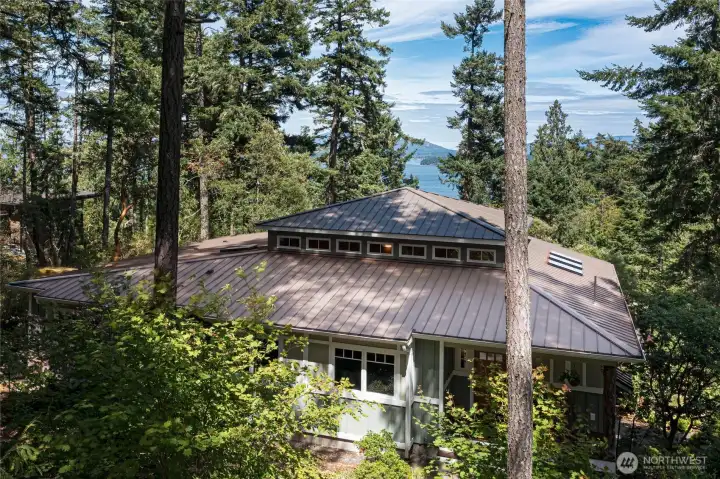 he home's striking standing-seam metal roof and thoughtfully designed clerestory window band are showcased from above, with the sparkling waters of the San Juan Islands providing a stunning natural backdrop through the evergreens. Skylights and premium roofing materials speak to the quality craftsmanship throughout this exceptional property. he home's striking standing-seam metal roof and thoughtfully designed clerestory window band are showcased from above, with the sparkling waters of the San Juan Islands providing a stunning natural backdrop through the evergreens. Skylights and premium roofing materials speak to the quality craftsmanship throughout this exceptional property.