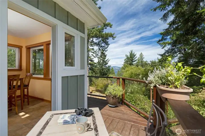 A charming secondary deck opens from a warm wood-trimmed interior dining nook off the kitchen, offering a private outdoor retreat to enjoy coffee and filtered water and mountain views. A charming secondary deck opens from a warm wood-trimmed interior dining nook off the kitchen, offering a private outdoor retreat to enjoy coffee and filtered water and mountain views.