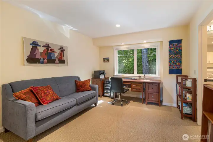 A versatile flex room currently serves as a comfortable home office and lounge, featuring colorful textile wall art, built-in desk, sofa seating, and peaceful wooded window views. This space adapts effortlessly as a den, guest room, or hobby studio to suit any lifestyle. A versatile flex room currently serves as a comfortable home office and lounge, featuring colorful textile wall art, built-in desk, sofa seating, and peaceful wooded window views. This space adapts effortlessly as a den, guest room, or hobby studio to suit any lifestyle.