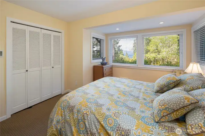 his inviting bedroom offers a peek-a-boo water view through its picture window, complemented by a full-width louvered bifold closet for ample storage. The soft yellow walls and neutral carpet create a calming atmosphere ideal for rest and relaxation. his inviting bedroom offers a peek-a-boo water view through its picture window, complemented by a full-width louvered bifold closet for ample storage. The soft yellow walls and neutral carpet create a calming atmosphere ideal for rest and relaxation.
