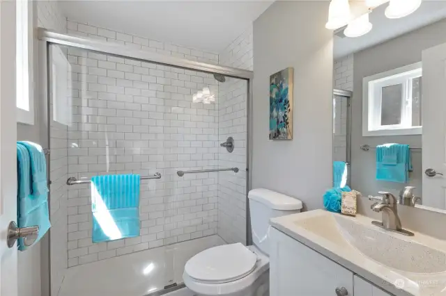 Primary bathroom has large subway tiled shower, deep sink & window for natural light