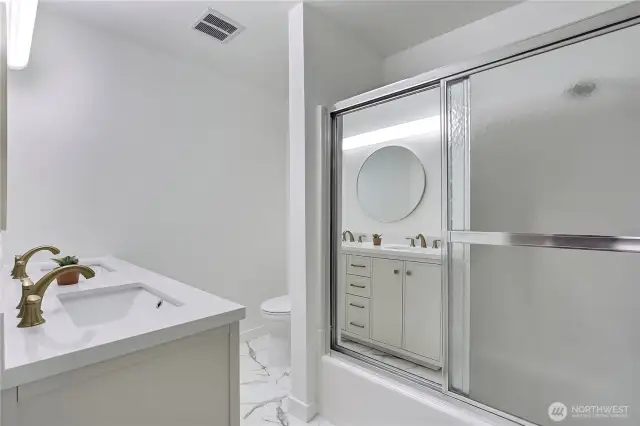 The guest bathroom also includes a convenient shower/tub combo with sliding glass doors—ideal for versatility and function. The updated finishes carry through, offering a cohesive design that blends style with practicality.